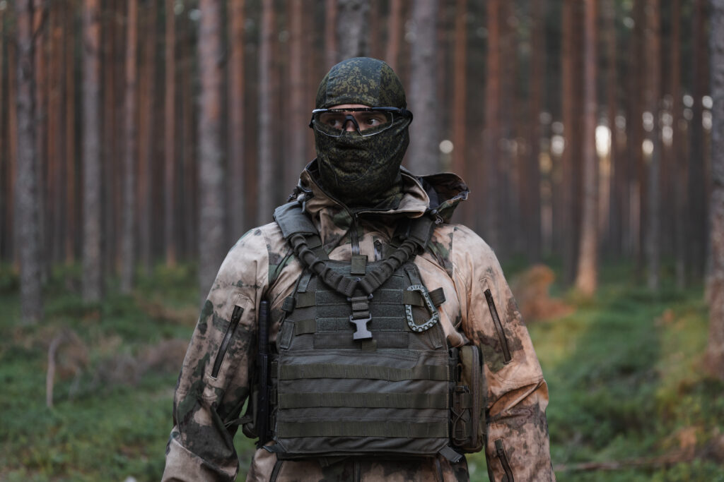 man in military camouflage and vest wearing a balaclava