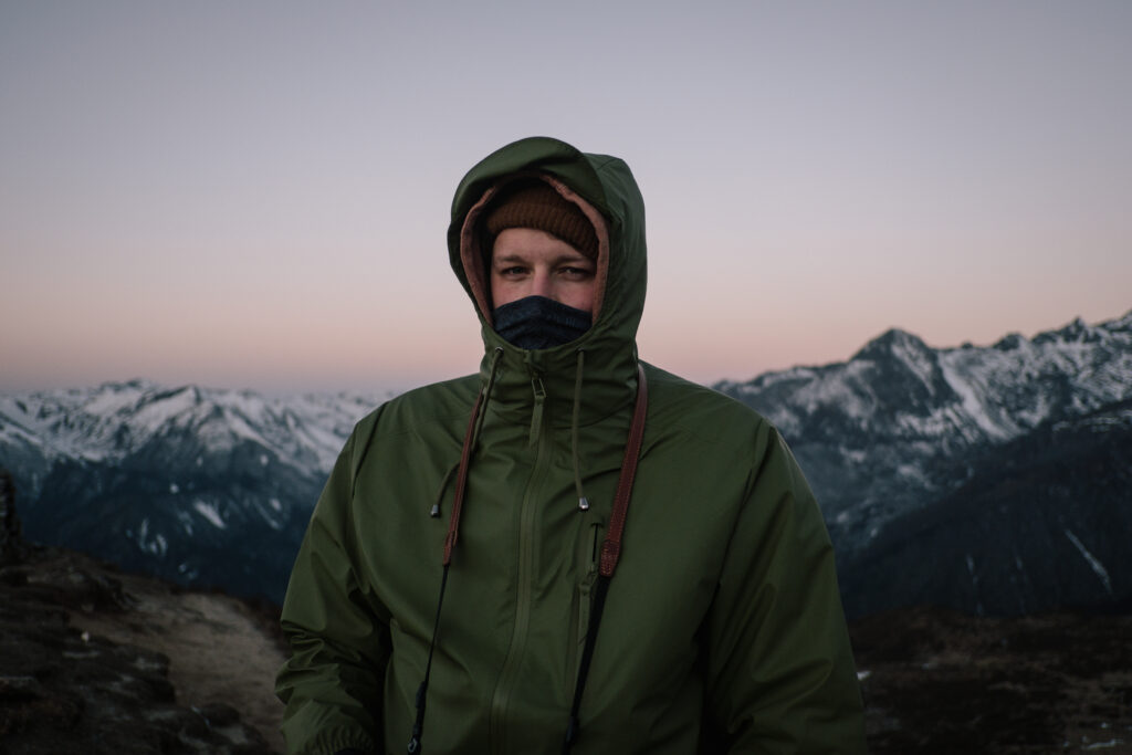 man standing in mountain background wearing multiple layers
